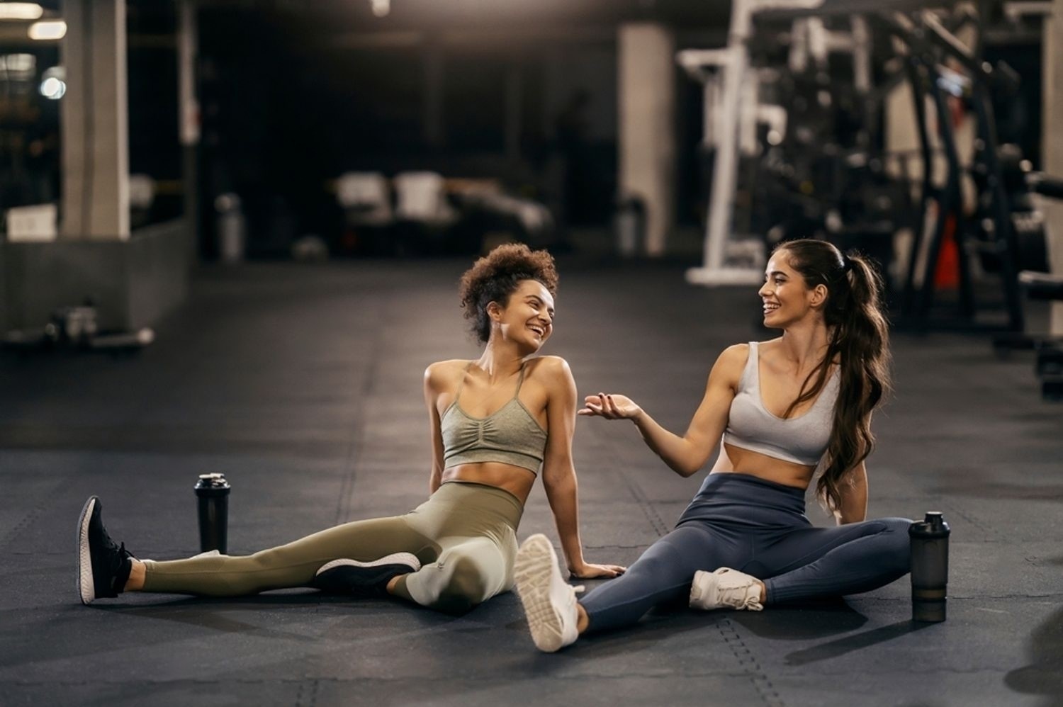 Two friends enjoying a break during their gym session, drinking water and staying hydrated while focusing on fitness, maximizing your workout with proper nutrition.